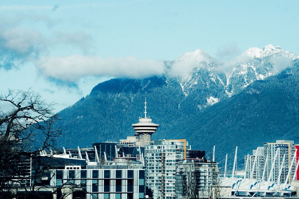 Vancouver skyline with Harbour Centre and snowy mountains.