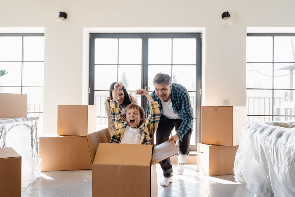 Photo of a kid playing with their parents inside a cardboard box.